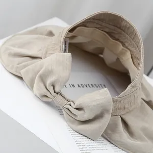 Elegant beige sun visor with pleated fabric texture and large bow decoration back view