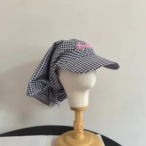 Dettaglio del cappello da sole a scacchi con ricamo Freedom rosa e protezione collo