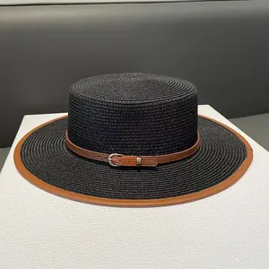 Detailed texture of black straw boater hat with brown leather band and gold buckle