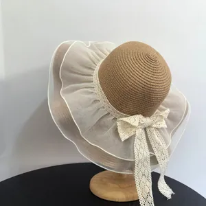 Detailed close-up of straw sun hat featuring wavy organza brim and large lace bow decoration