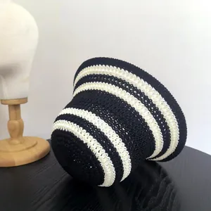 Dettaglio ravvicinato di cappello a righe in maglia con trama all'uncinetto su legno