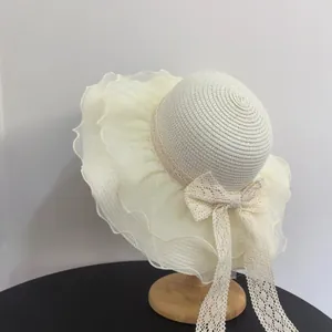 Detailed view of wide brim straw hat with organza ruffles and delicate lace ribbon ties