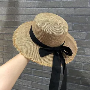Cappello di paglia a testa piatta con fiocco nero e bordi sfrangiati per mare estate