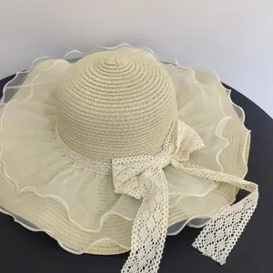 Detail of beige straw hat with organza wavy brim and delicate white lace bow accent