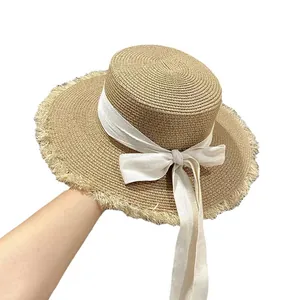 Cappello di paglia a testa piatta con bordi sfilacciati e fiocco in nastro per estate