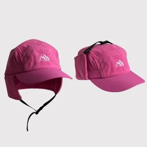 Detail of magenta fleece trapper hat with earflaps and mountain embroidery for winter