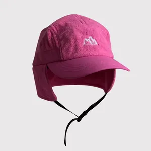 Detail of deep pink fleece earflap hat featuring mountain embroidery and windproof strap