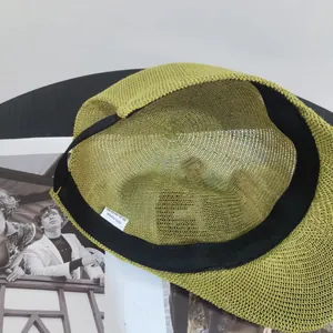 Detail view of woven green straw sun hat featuring 100% paper material and black inner sweatband