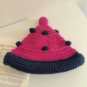 Close-up of handmade chunky knit beanie in magenta and navy blue with wool pom-poms