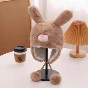 Detalle del gorro de peluche marrón con orejas de conejo para niños y suaves pompones