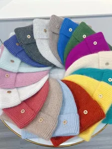 Plano cenital de gorros de punto en varios colores con logo B dorado en suave piel de conejo