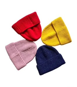 Detalle de cuatro gorros de punto acanalado en colores rojo, azul marino, amarillo y rosa