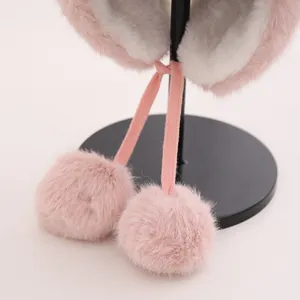 Detalle del gorro de felpa rosa con orejeras, forro polar blanco y pompones