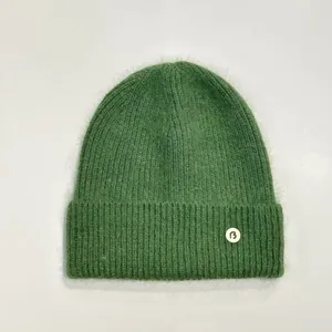 Primer plano del gorro de punto verde con suave textura de pelo y parche de logo B