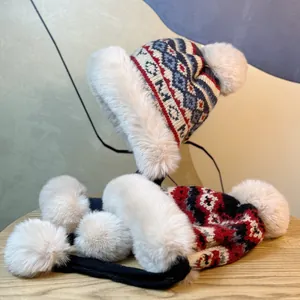 Macro detail of winter knit earflap hat with thick faux fur lining and white pom-poms