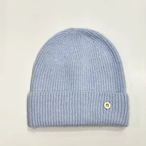 Detalle del gorro de punto azul cielo con un parche de logotipo redondo blanco y letra B