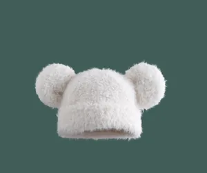 Close-up of white plush knit hat featuring large soft pom-poms and warm fuzzy texture