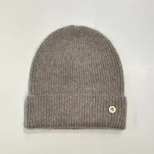 Detalle macro del gorro de punto gris pardo con textura suave y parche decorativo de la B