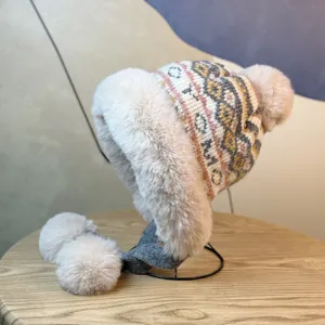 Detail of winter knit trapper hat with beige faux fur lining and plush pompom ties