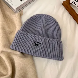 Detalle del gorro lavanda con bordado de gato negro y texto IT'S A CAT bordado