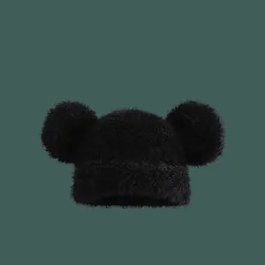 Detailed close-up of fluffy black knit beanie with soft plush texture and large pom-pom ears