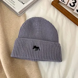 Detalle del gorro de punto acanalado morado con bordado negro y borde doblado