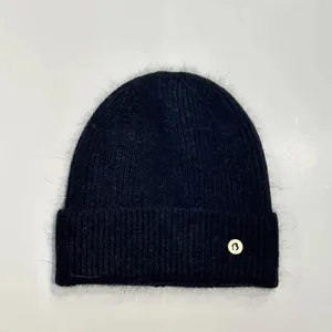 Primer plano detallado del gorro de punto de angora negro con parche de letra B y textura suave