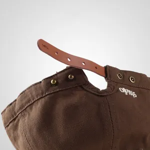 Detail of brown canvas cap featuring adjustable leather strap and Studio embroidery
