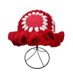 Detail of handmade crochet bucket hat with floral pattern and ruffled edges in red and white