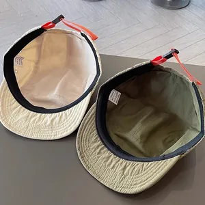 Dettaglio cappellini in nylon traspirante a tesa corta con coulisse regolabile arancione