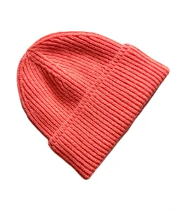 Detalle macro del gorro de punto coral con textura acanalada y dobladillo grueso