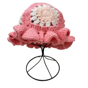 Detailed crochet texture of pink handmade sun hat featuring floral knit and ruffled brim