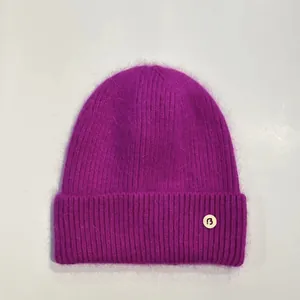 Detalle del gorro de punto violeta oscuro con textura peluda y parche con logo B
