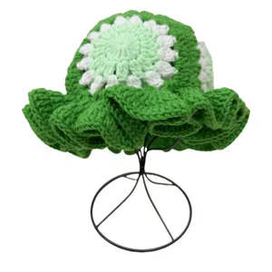Detailed knit texture of green crochet bucket hat with wavy brim and floral top pattern