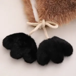 Detail of plush pom-pom drawstrings with faux animal paw design on a warm winter hat