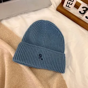 Detailed knit texture of a blue beanie with a signature R letter embroidery on soft fabric