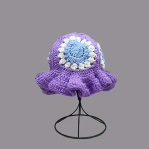 Detail of crochet bucket hat featuring blue floral pattern and wavy ruffled purple brim