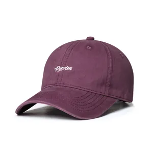 Detail of burgundy baseball cap featuring white embroidered cursive letter branding