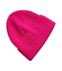Detalle del gorro de punto rosa intenso que muestra la textura de canalé y el dobladillo