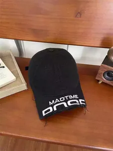 Close-up of MADTIME embroidery and distressed edges on a washed black cotton baseball cap