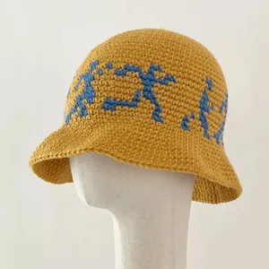 Detailed knit texture and blue pixel art pattern on a yellow crochet bucket hat