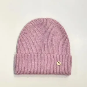 Primer plano de gorro rosa de pelo de conejo con textura suave y detalle de letra B