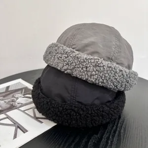 Close-up of grey and black fleece-lined Miki hats in a cozy lifestyle setting