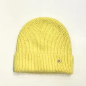 Primer plano del gorro de punto amarillo esponjoso con hebilla metálica letra B