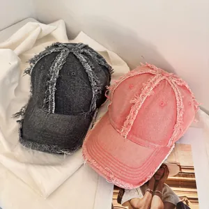 Vintage distressed denim baseball caps in dark grey and pink with frayed edges and fringe