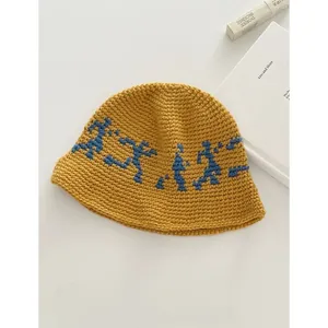 Detail of mustard yellow knit bucket hat with blue abstract figure embroidery pattern