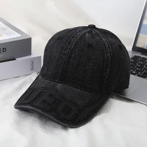 Close-up of black washed denim baseball cap with embossed UEQ lettering detail