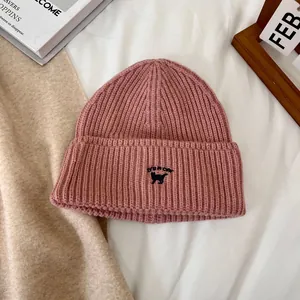 Detalle de gorro de punto rosa con textura de canalé y bordado de gato adorable