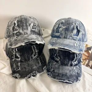 Dettaglio di quattro cappellini da baseball in denim invecchiato con lavaggi vintage e strappi