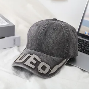 Detail of UEQ letter embroidery on washed denim baseball cap with vintage finish